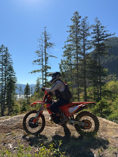 Thomas on a dirt bike beside a forest trail